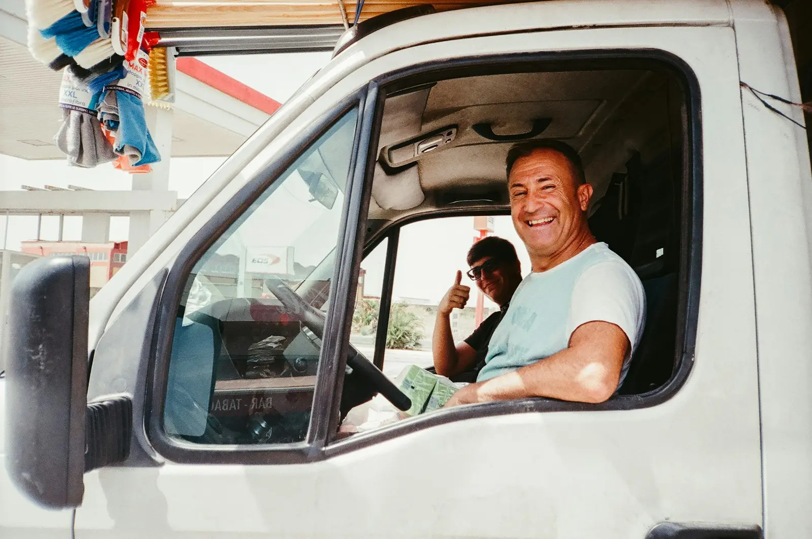 A smiling van driver at the wheel, giving a thumbs up